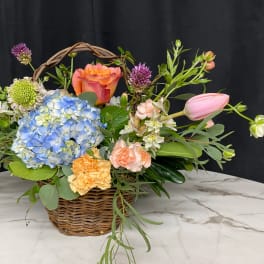 Basket arrangement with blue hydrangea, roses, tulips, and carnations