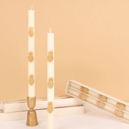 White taper candles with gold pineapple decorations in boxes
