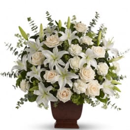 White lilies and cream roses arranged in a brown urn vase