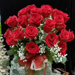 Bouquet of red roses in a glass vase with a red ribbon