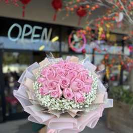 Bouquet of pink roses with white filler flowers and pastel wrapping