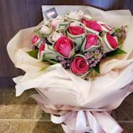Bouquet of pink roses wrapped in white paper with a pink ribbon