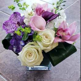 Bouquet of purple and pink flowers with white roses in a glass vase