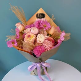 Pink and peach mixed bouquet wrapped in tan paper with a ribbon