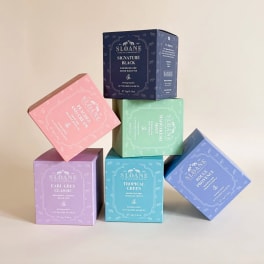 Stacked colorful Sloane tea boxes on a plain background