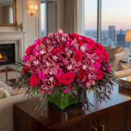 Pink roses and orchids arranged in a square glass vase