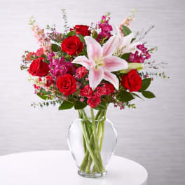 Bouquet of red roses and pink lilies in a clear glass vase