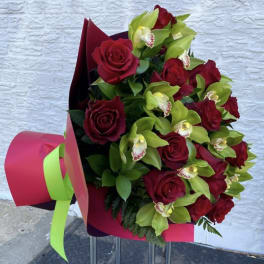Bouquet of red roses and green orchids wrapped in pink paper