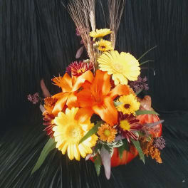 Orange and yellow floral arrangement in a pumpkin container
