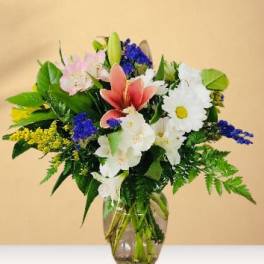 Mixed bouquet of lilies, daisies, and blue flowers in a glass vase