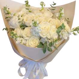 Bouquet of white roses and pale blooms wrapped in beige paper