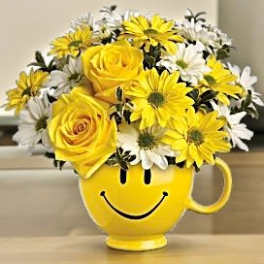 Yellow smiley-face mug filled with yellow and white flowers