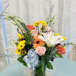 Mixed bouquet in a clear glass vase with lilies, roses, gerbera daisies, and hydrangea