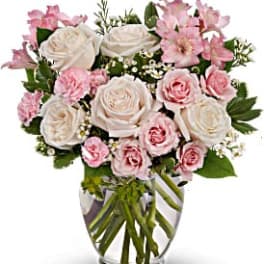 Pink and white roses arranged in a clear glass vase