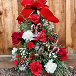Christmas tree arrangement with red and white flowers, candy canes, and a large red bow