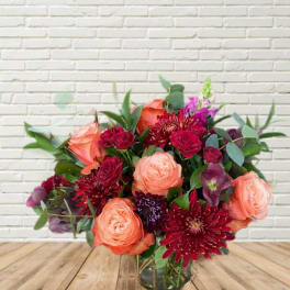Bouquet of peach and burgundy flowers in a glass vase