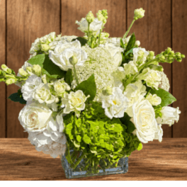 White roses and green hydrangeas in a clear glass vase
