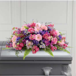 Pink and purple floral casket spray on a gray casket