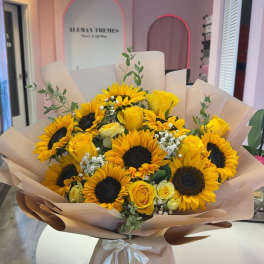 Bouquet of yellow sunflowers and roses wrapped in blush paper