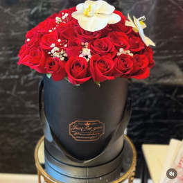Red roses in a black hatbox with white orchids