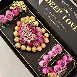 Black gift box with pink roses and chocolates arranged in compartments