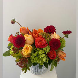 Mixed bouquet of red, orange, and yellow flowers in a silver vase