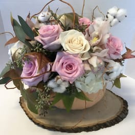 Pink and white roses arranged in a low bowl with cotton accents