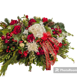 Large holiday floral arrangement with red and white flowers and a red ribbon
