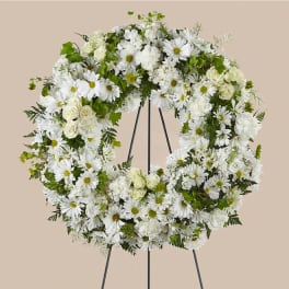 White floral wreath on a black stand with daisies and roses