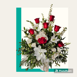 Red roses and white lilies in a white vase with greenery