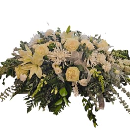 Cream floral casket spray with roses, lilies, and white blooms