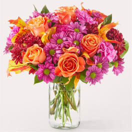Bouquet of orange roses and pink daisies in a clear glass vase