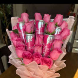 Pink roses arranged with pink cans in a wrapped bouquet