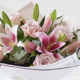 Bouquet of pink roses and lilies wrapped in white paper
