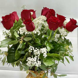 Red roses arranged in a marbled glass vase with white filler flowers