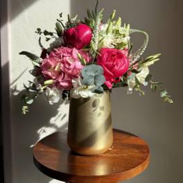 Pink and white floral arrangement in a gold vase