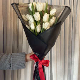Bouquet of white tulips wrapped in black paper with a red ribbon
