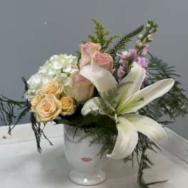 Mixed bouquet with white lilies, roses, and hydrangea in a white vase