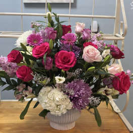 Mixed bouquet of pink, white, and purple flowers in a white vase