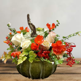 Orange and white floral arrangement in a green pumpkin vase