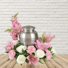 Pink and white floral arrangement around a silver urn