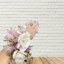 Pink and white floral wrist corsage with ribbon on a hand