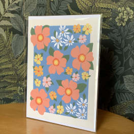 Floral greeting card with coral, yellow, white, and pink flowers on a blue background