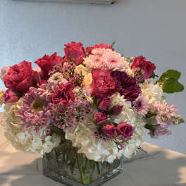 Pink and white mixed flower arrangement in a square glass vase