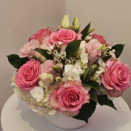 Pink roses and white hydrangeas arranged in a white bowl vase