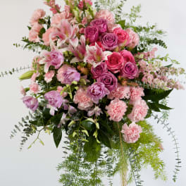 Pink and purple floral spray on a stand with trailing greenery