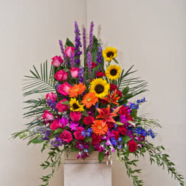 Tall colorful floral arrangement with roses, sunflowers, orchids, and lilies