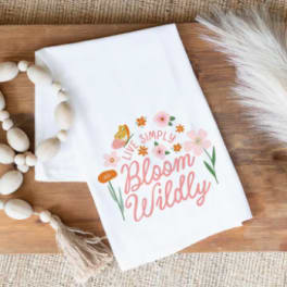 White shirt with floral "Live Simply Bloom Wildly" graphic