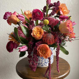 Colorful bouquet of orange and magenta flowers in a blue-and-white vase