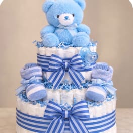 Blue teddy bear atop a diaper cake with striped ribbons and baby booties